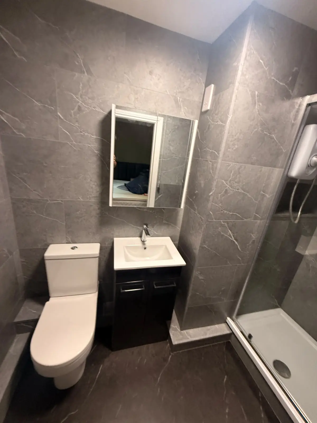 Compact Durham bathroom with SPC marble-effect walls, dark floor tiles, vanity and glass shower cubicle
